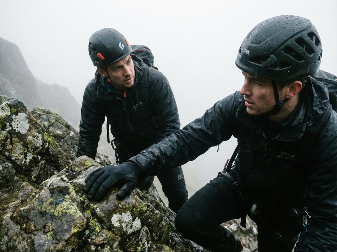 Instructor guiding a climber on a misty mountain scramble — the human dynamic at the heart of SWC training