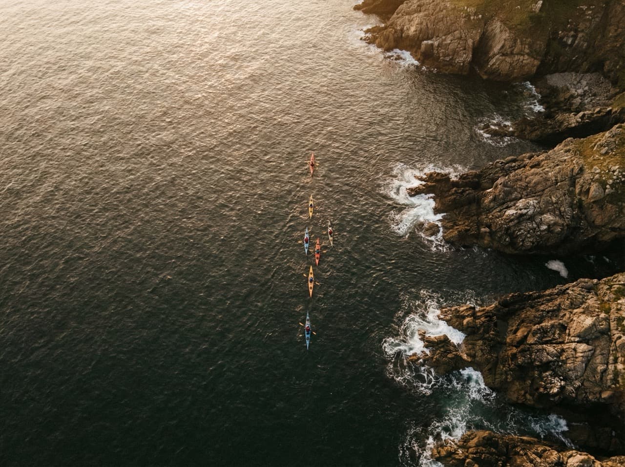 Aerial view of kayakers in formation along rugged coastline